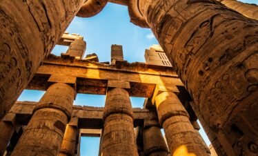 View of the majestic ancient columns in Karnak Temple, Egypt, under a clear sky.